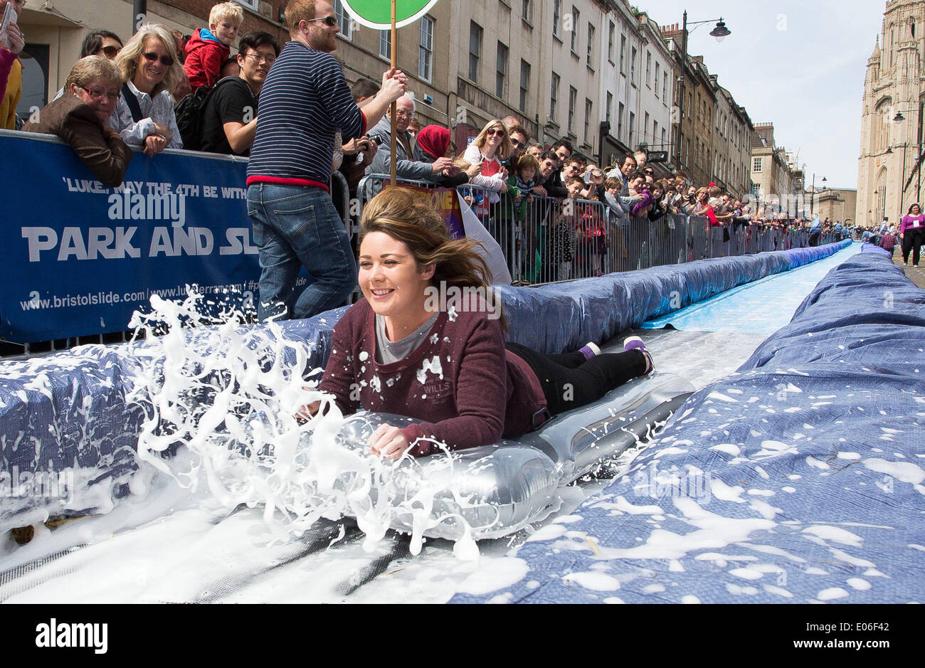 Bristol, UK. 04th May, 2014. People speed down a 90m water slide erected on Park Street in Bristol. Artist Luke Jerram organised the event where 300 people will hurtle down plastic sheets soaked in washing-up liquid and bordered with 400 hay bales. 4 May 2014 Credit:  Adam Gasson/Alamy Live News Stock Photo