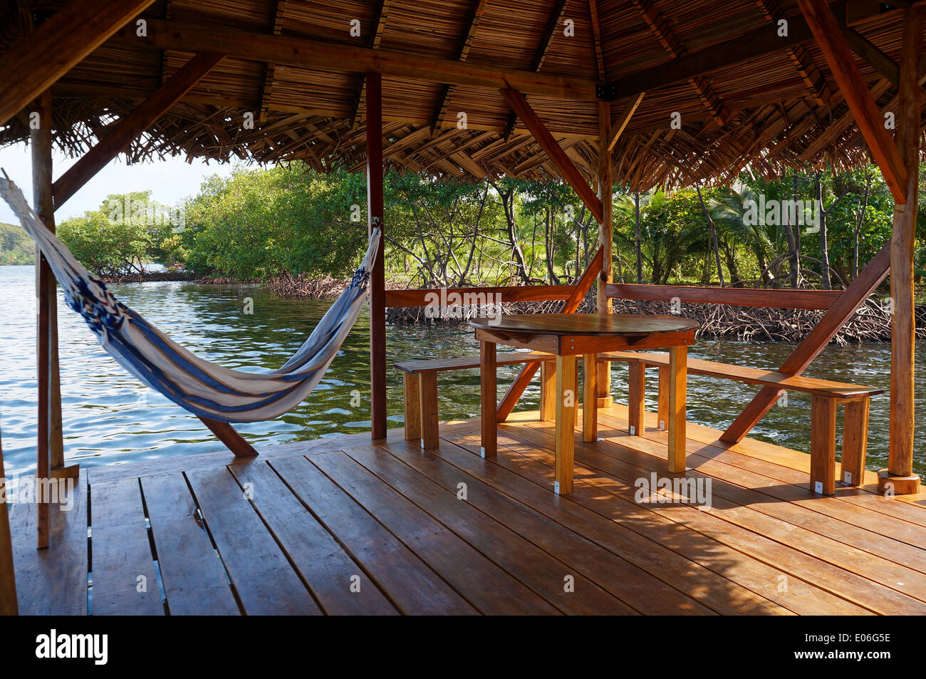 Peaceful scene on a palapa over water with hammock and a table, Caribbean sea Stock Photo