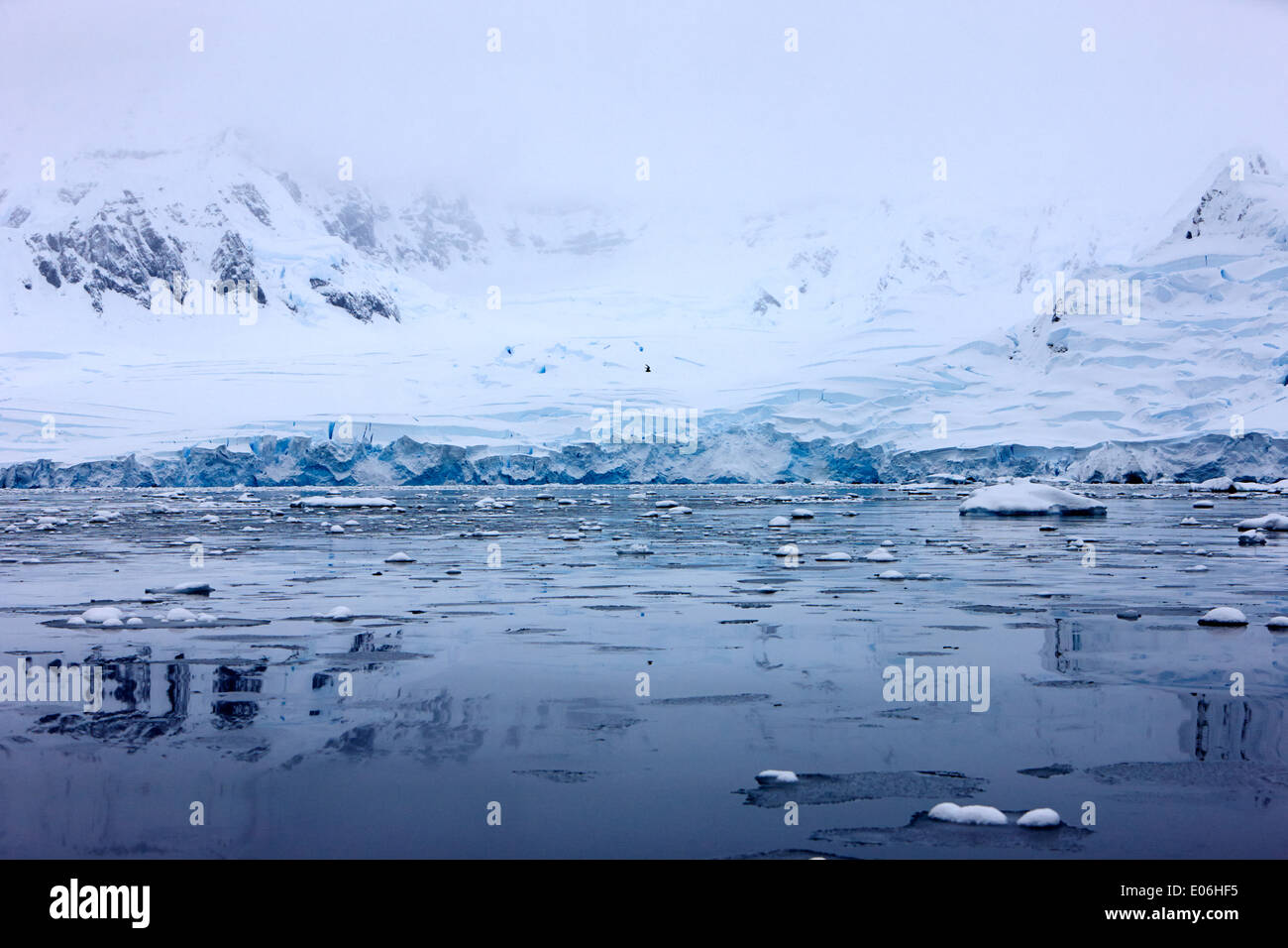 snow covered ice shelf glacier falling into the sea with brash ice at