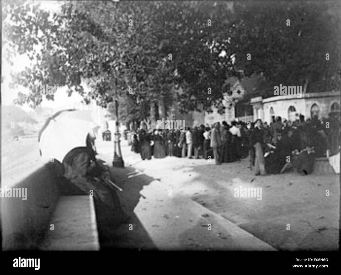 A photograph from August 23, 1898, showing pilgrims at the grotto in Lourdes, a significant site for religious pilgrimage in France, surrounded by trees and a path. Stock Photo