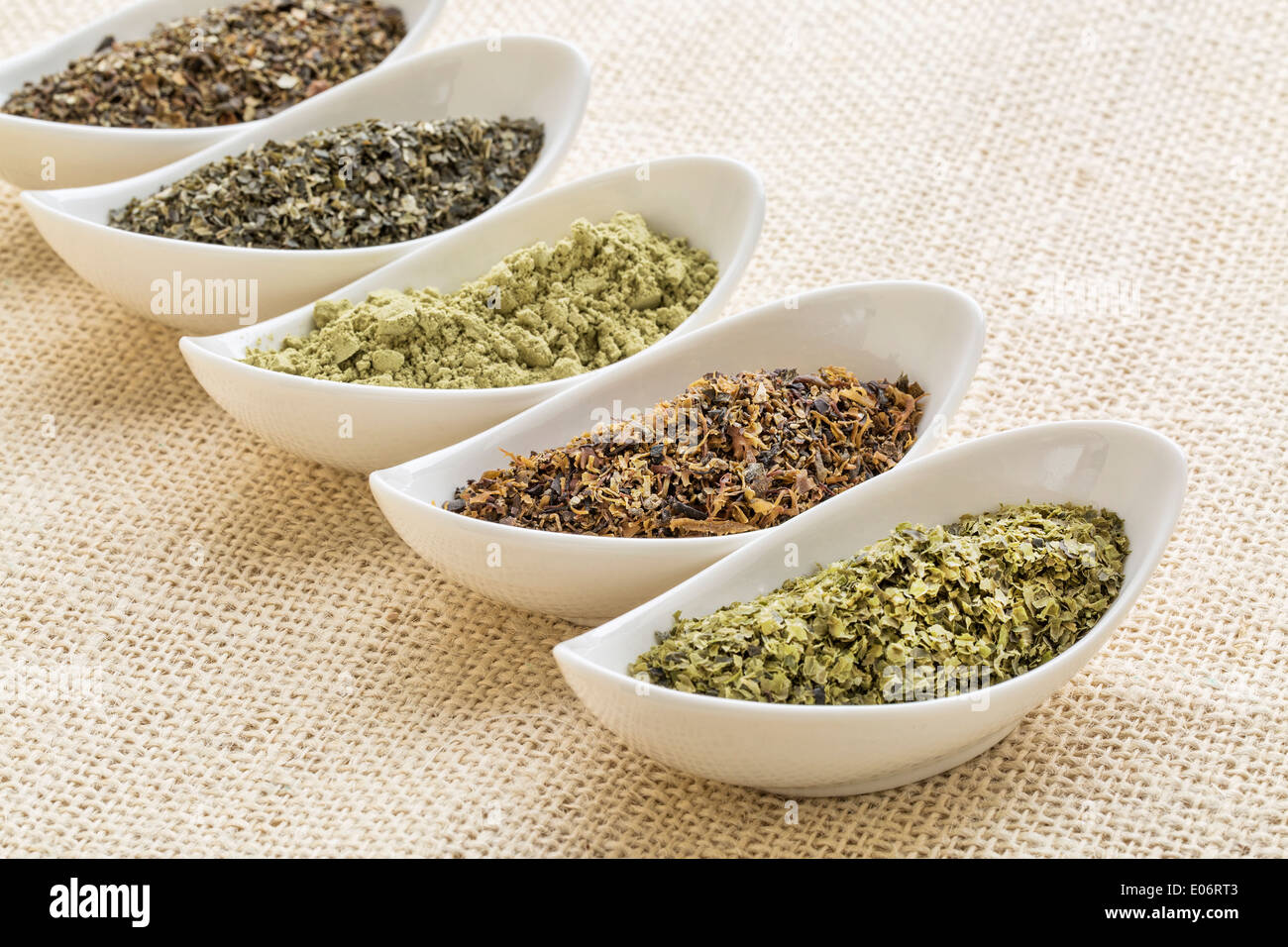 bowls of seaweed diet supplements (bladderwrack, sea lettuce, kelp, wakame and Irish moss) on burlap canvas Stock Photo