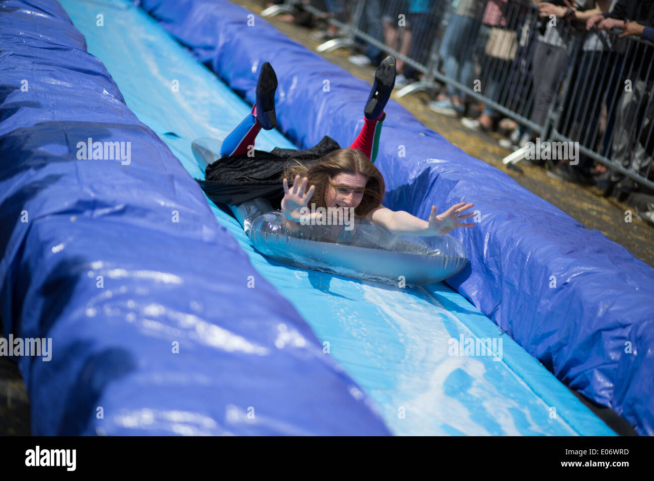 Bristol's Park Street was closed for a giant water slide. Woman braces for impact dressed as super hero. Stock Photo