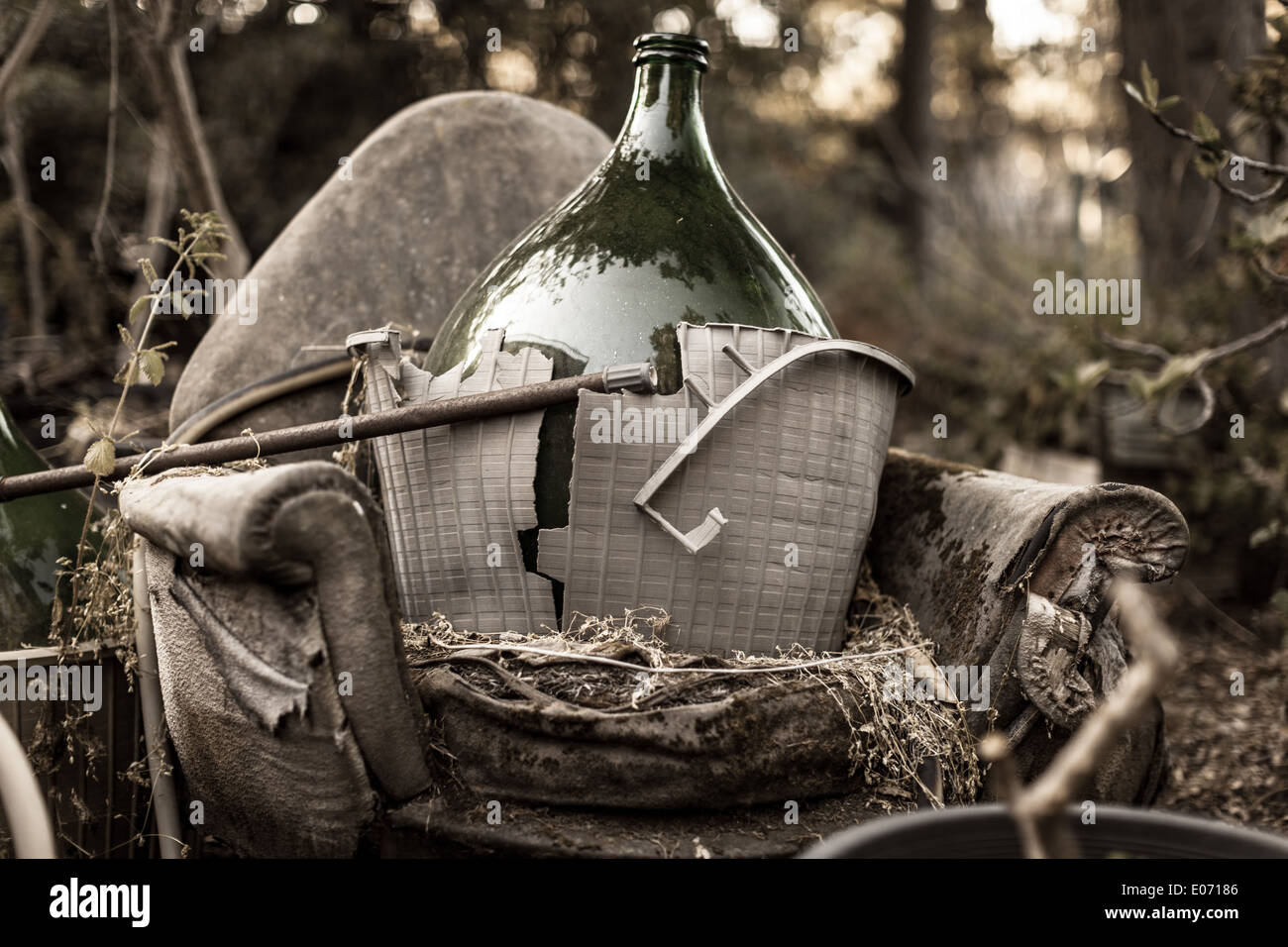 a dirty and rotten armchair trashed in a backyard along with some garbage Stock Photo