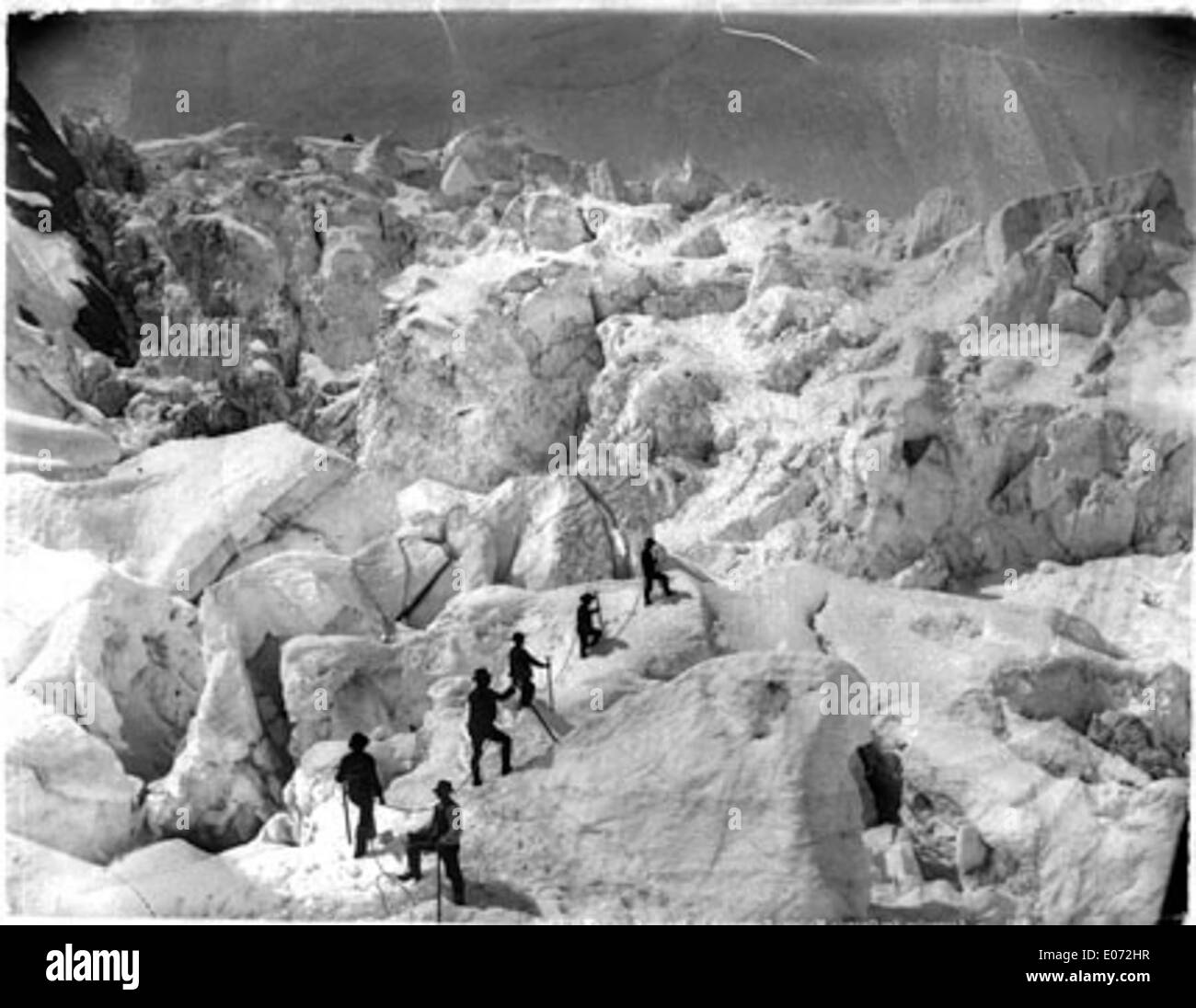 This photograph captures the ascent of alpinists on the Grands-Mulets route in the French Alps. It is a historic portrayal of mountaineering during the early stages of alpine exploration. Stock Photo