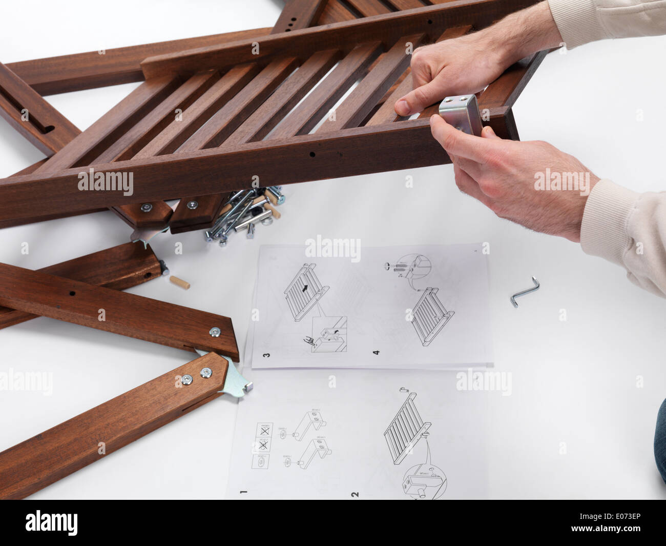 Person assembling IKEA furniture parts with instructions Stock Photo