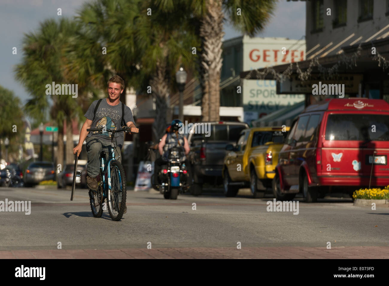 Teenage peddling Bicycle on Main Street Leesburg, Florida USA Stock