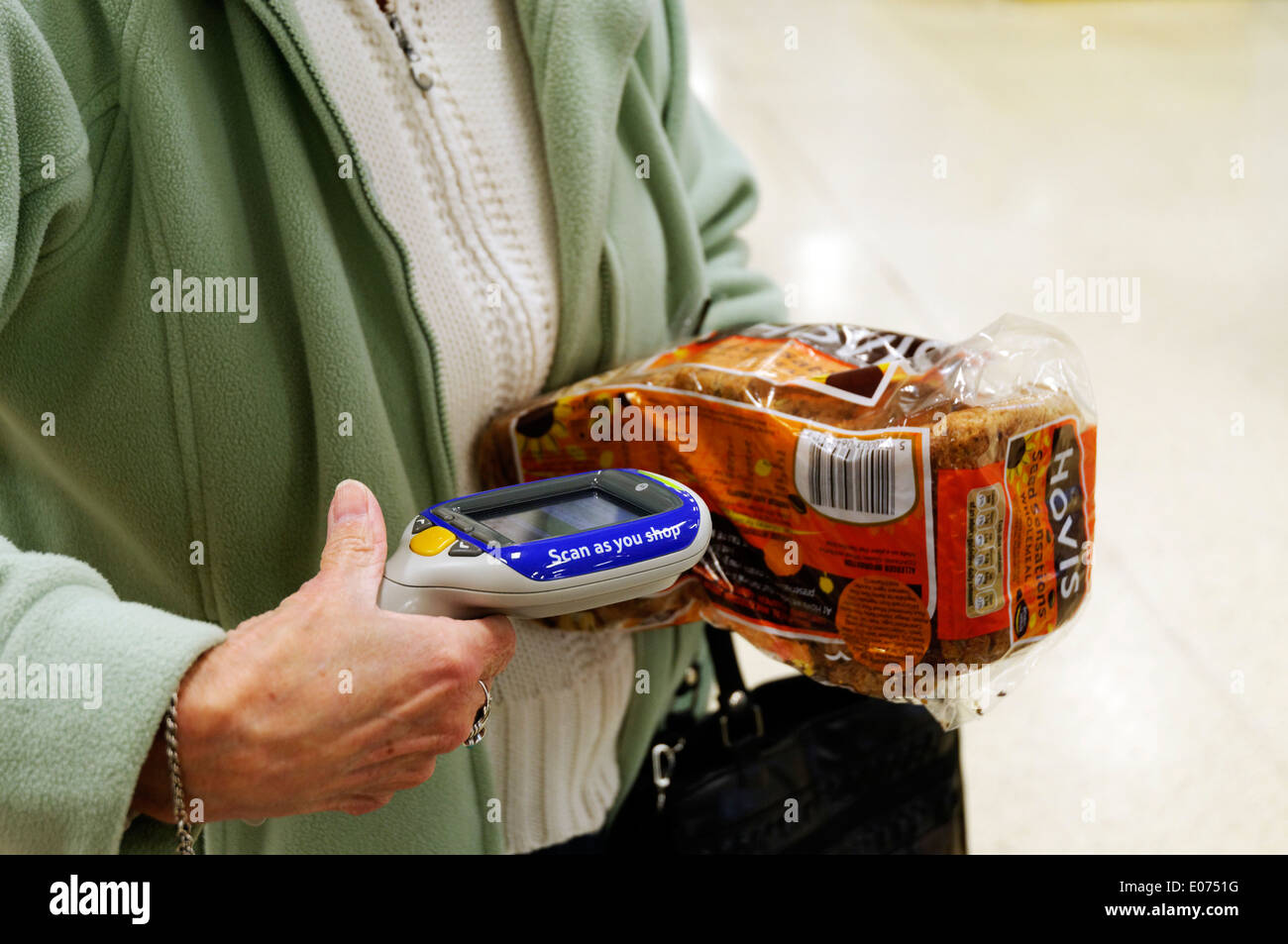 An older woman's hands scanning a loaf of bread in Tesco Scan as you Shop Stock Photo