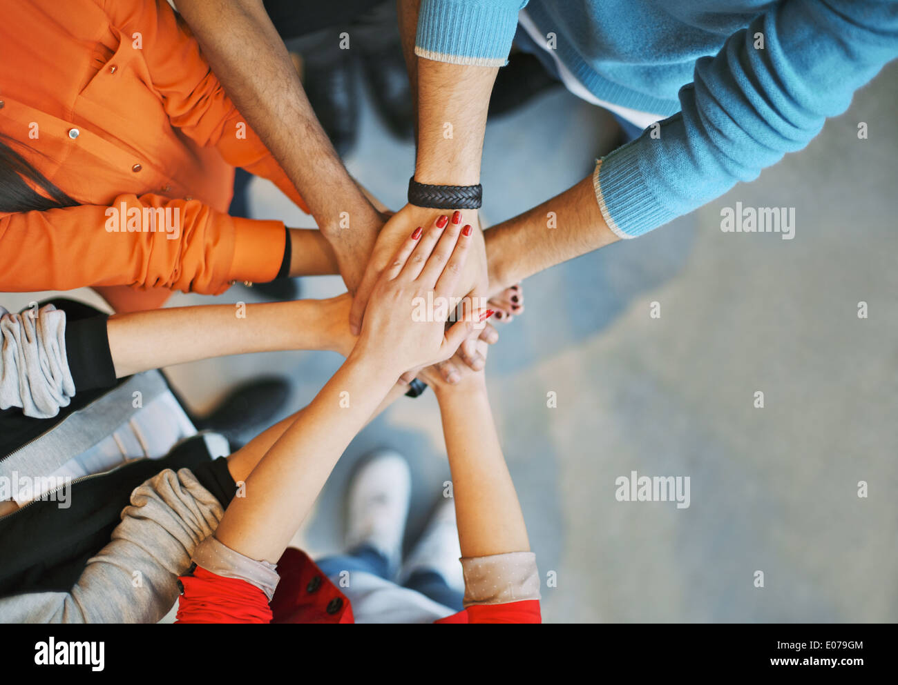 Top view image of group of young people putting their hands together. Friends with stack of hands showing unity. Stock Photo