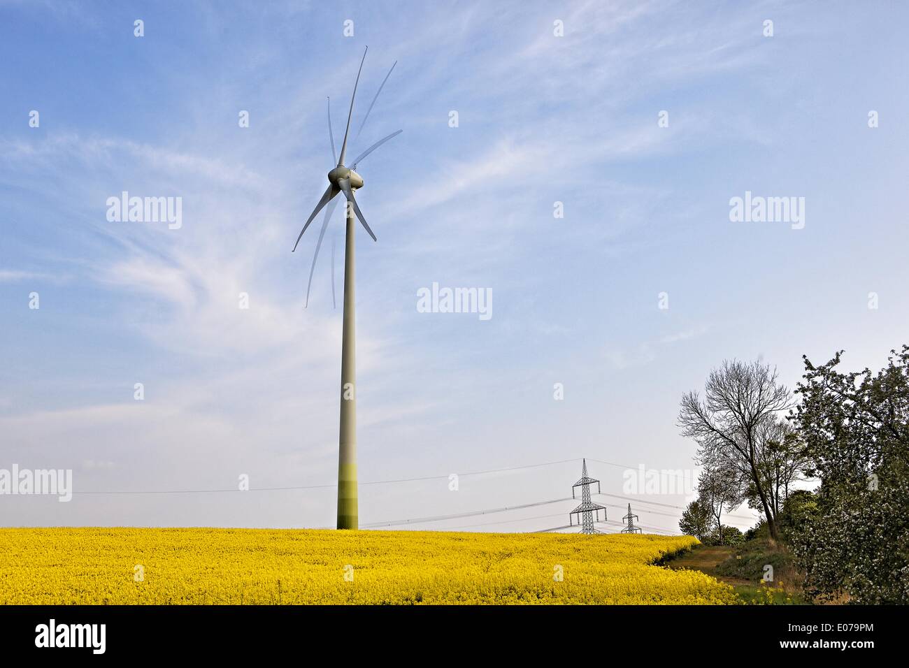 Wind power unit right from a electricity pylon under blue sky trees (triple exposure), 29.04.2014 Stock Photo