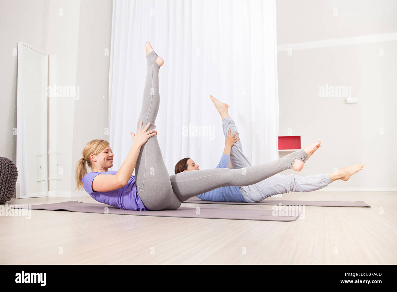 Women doing Pilates exercise, stretching out legs Stock Photo