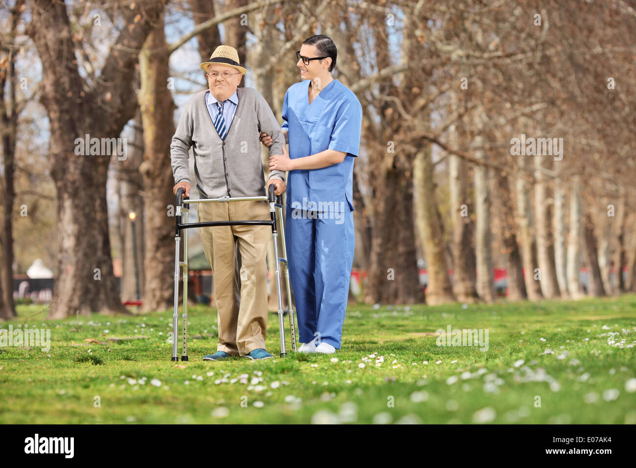 Medical professional helping a senior with walker in park Stock Photo