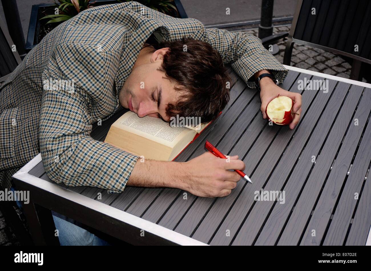 Berlin, Germany. 17th Sep, 2013. ILLUSTRATION - A man fell asleep at a table on a book with an apple and a pen in his hands in Berlin, Germany, 17 September 2013. Photo: Berliner Verlag/Steinach - ATTENTION! NO WIRE SERVICE -/dpa/Alamy Live News Stock Photo