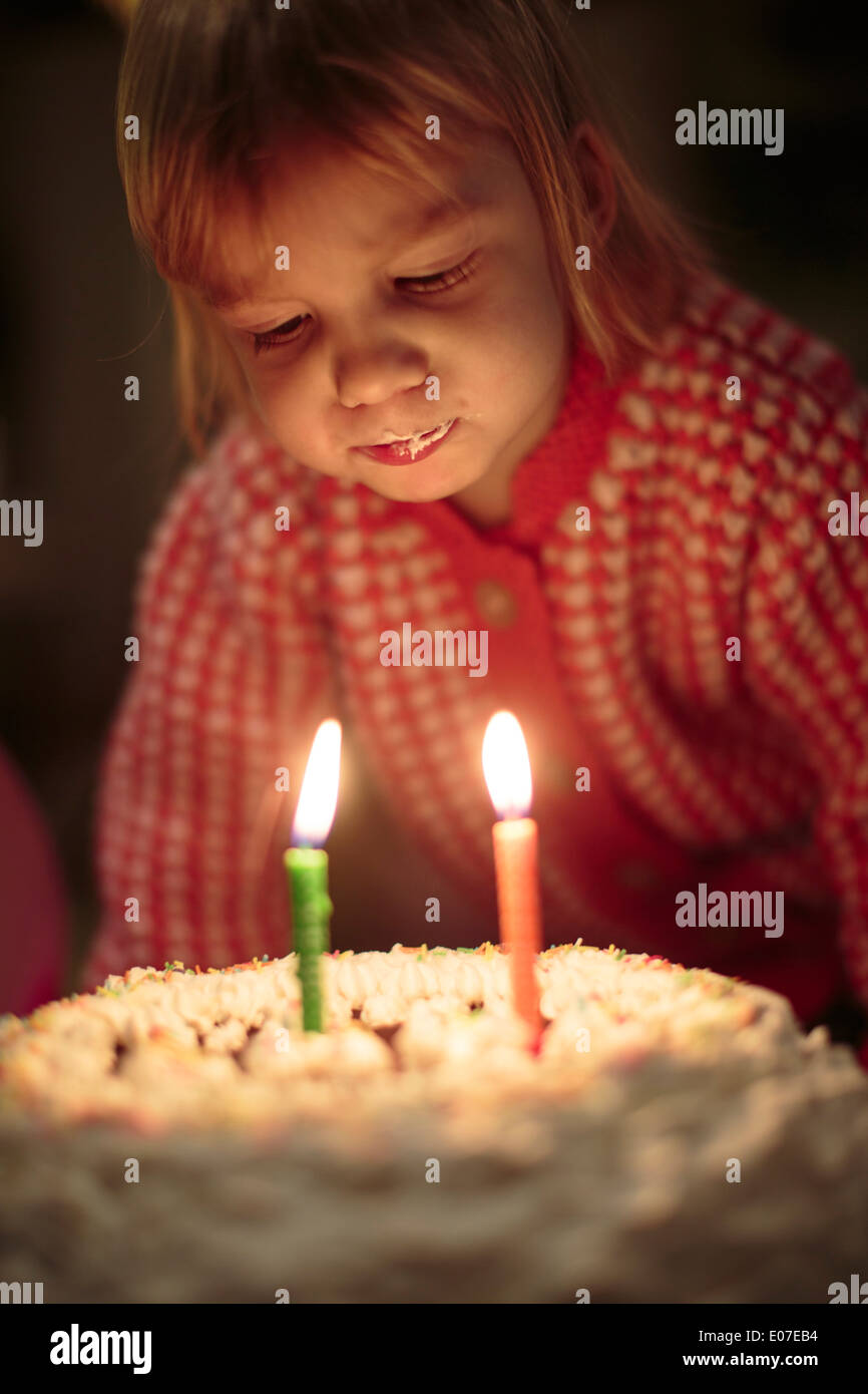 Little girl blowing out birthday candles on cake Stock Photo Alamy