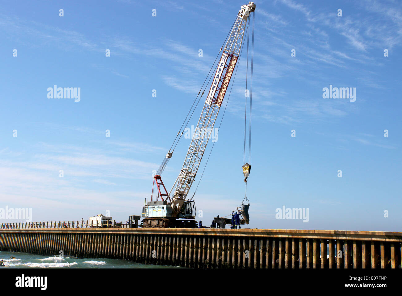 Four unknown workers and mobile crane operate on site constructing new