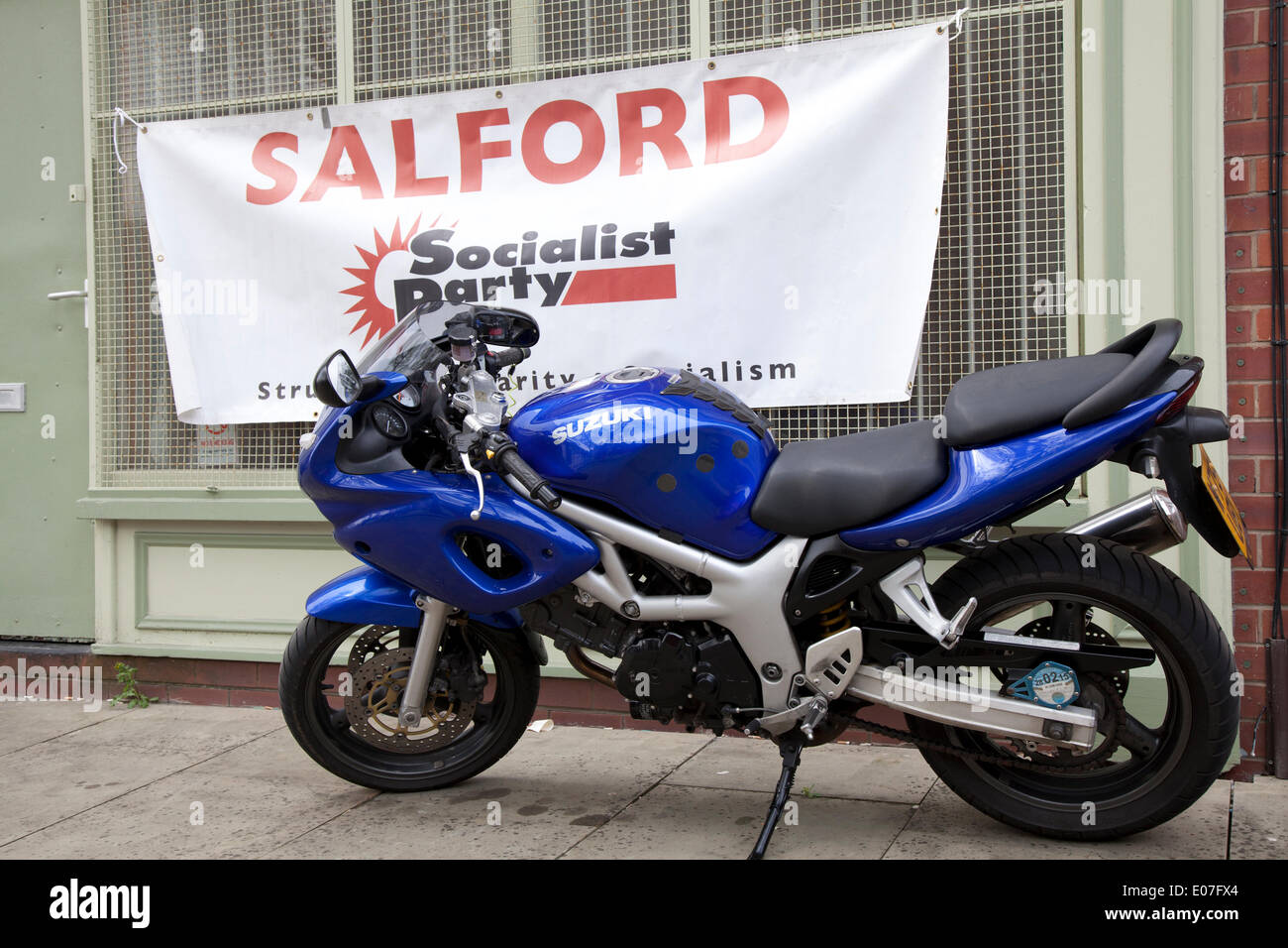 Suzuki SV650S motorcycle in front of Socialist Rally banner inSalford, Manchester, UK Trappings of Capitalism at Salford's annual May Day Rally.  Manchester, Salford, Bury and Oldham Trades Union Councils organized this year's May Day event, with the message `A Better Future for All Our Communities' to celebrate international workers day. Stock Photo