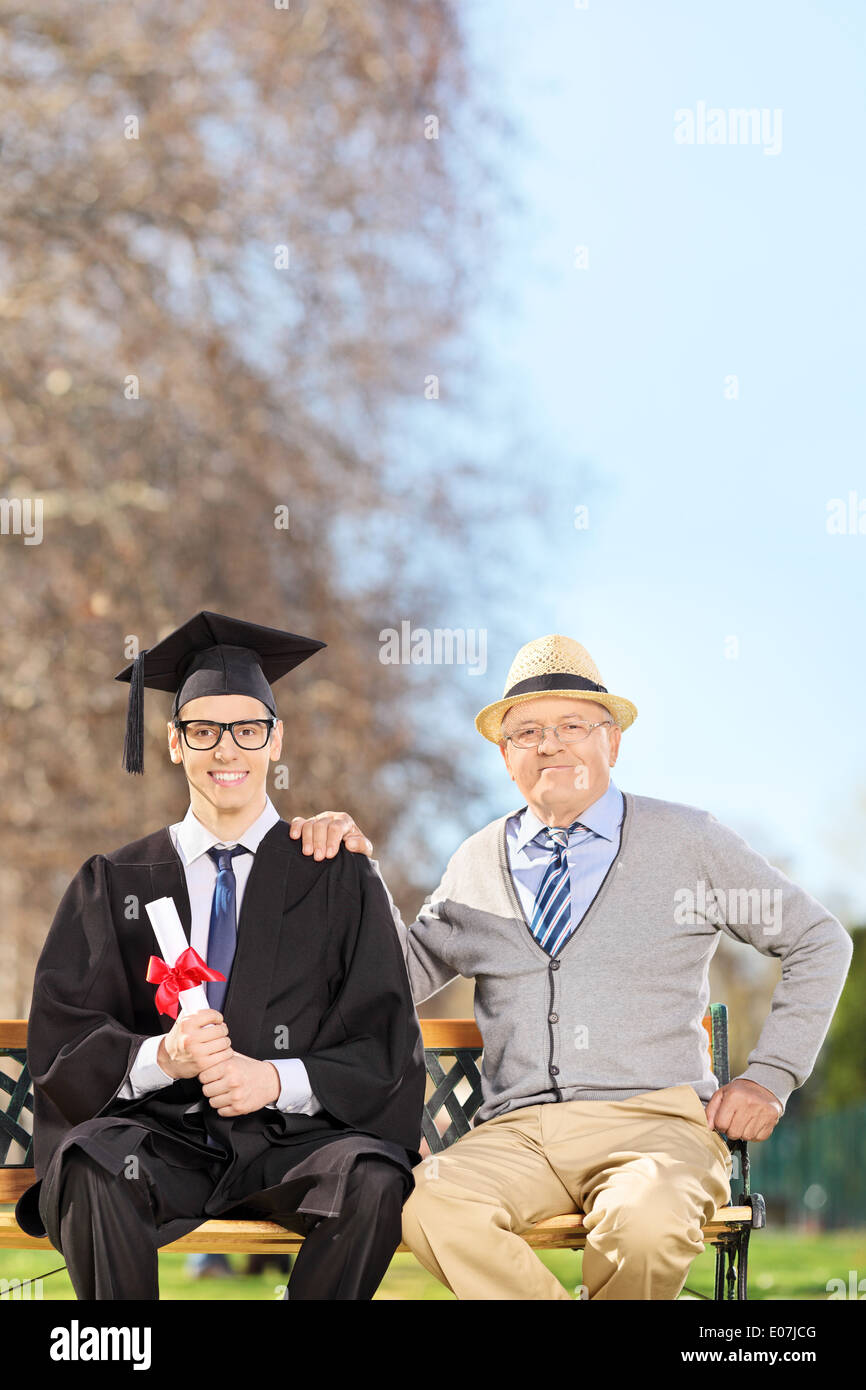 college graduate posing with his father outdoors E07JCG