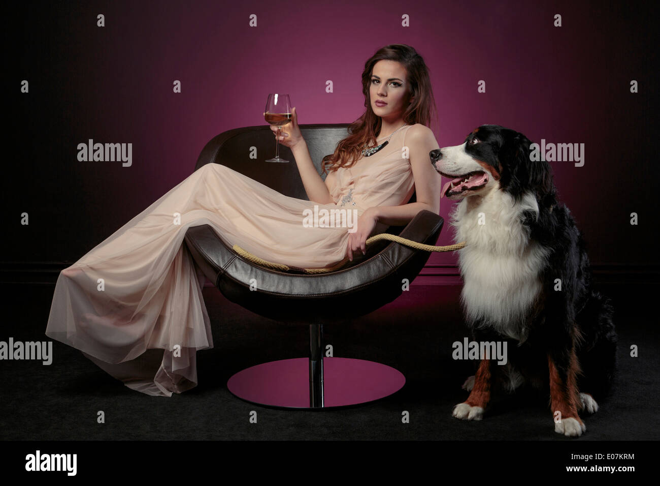 Woman drinking a glass of wine alongside huge dog Stock Photo