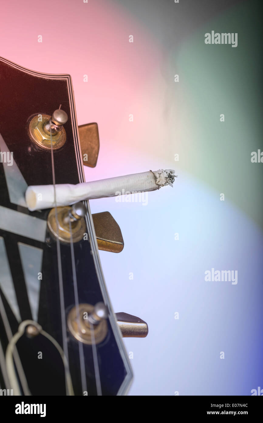 cigarette in guitar headstock close up of a guitar headstock with burning cigarette sticking under one  string Stock Photo