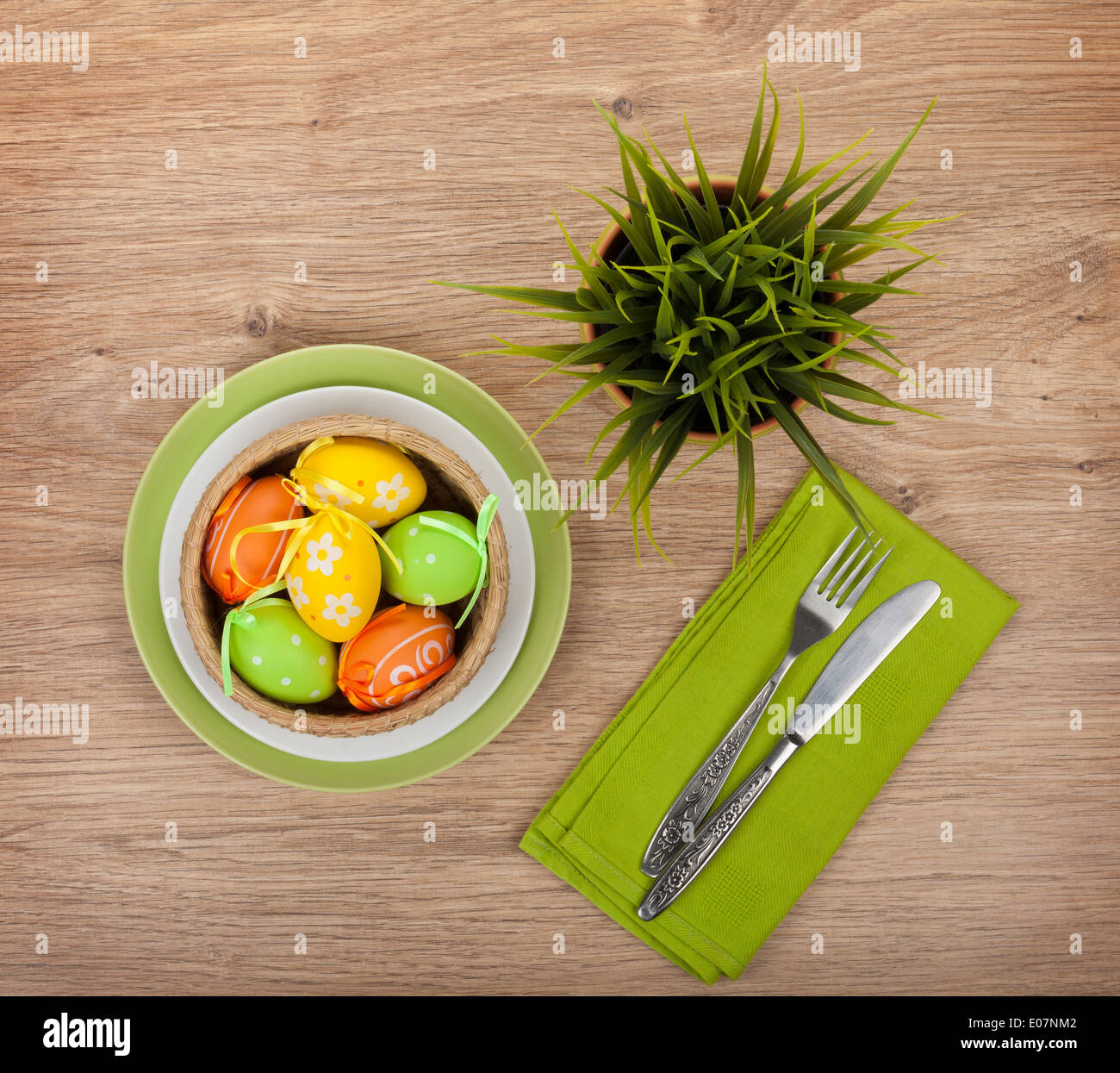 Easter eggs with silverware and potted flower over wooden table background Stock Photo