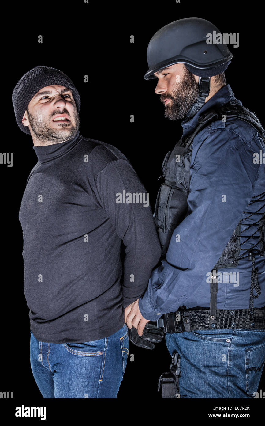 a cop wearing the SWAT tactical vest arresting a burglar Stock Photo