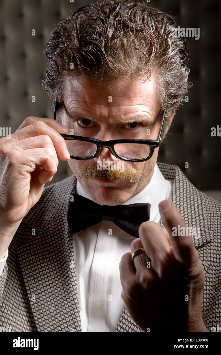 authoritative figure or principal beckoning angrily wearing bow tie and glasses Stock Photo