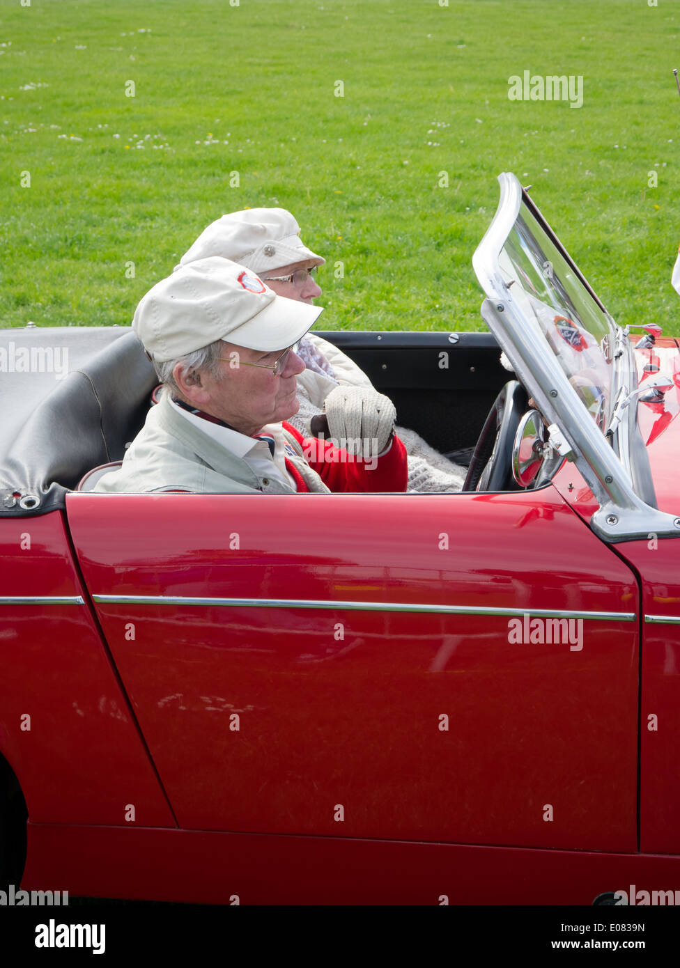 A man driving a red 1962 Mk1 MG Midget with a female passenger Stock Photo