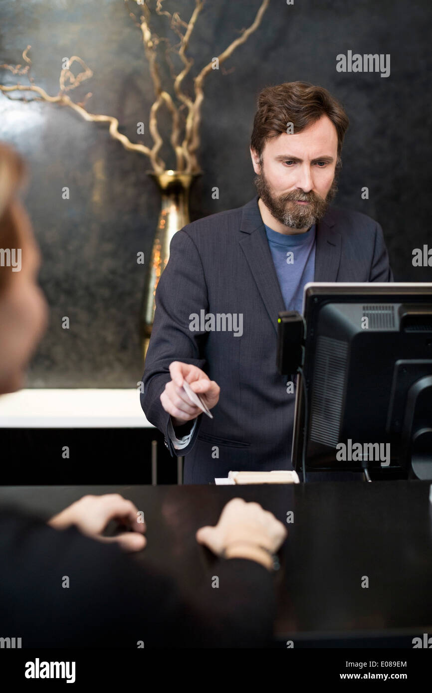 Male receptionist accepting payment through credit card from customer in hotel Stock Photo