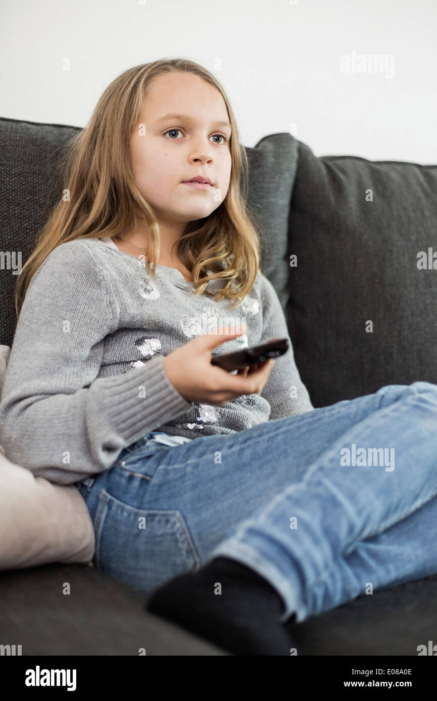 Girl watching TV on sofa at home Stock Photo - Alamy