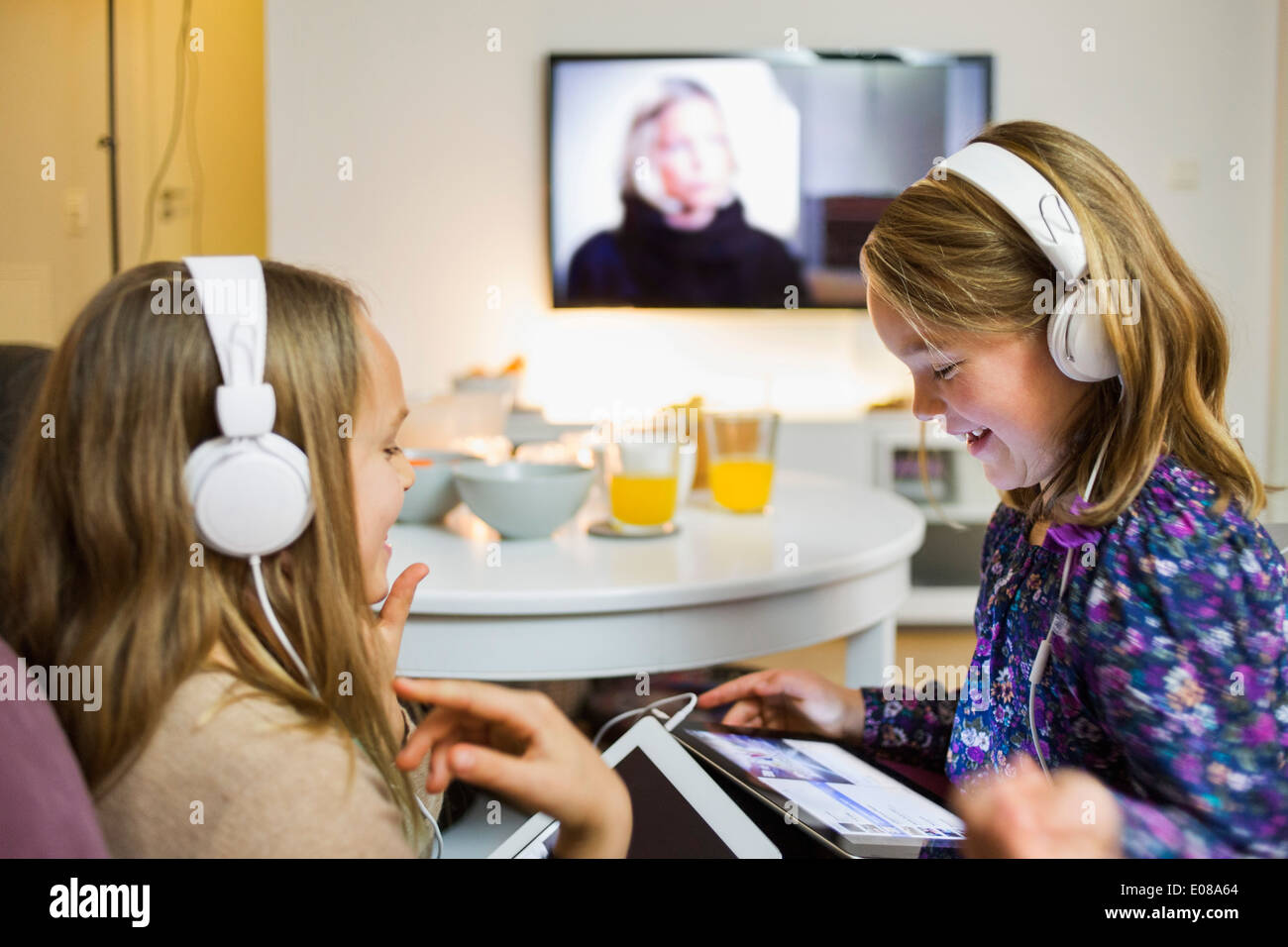 Happy sisters listening music on digital tablets in living room Stock ...
