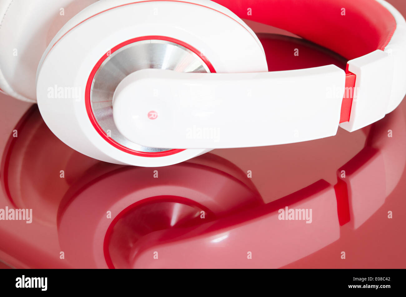 Red and white colorful headphones on bordo laptop mirrored surface Stock Photo