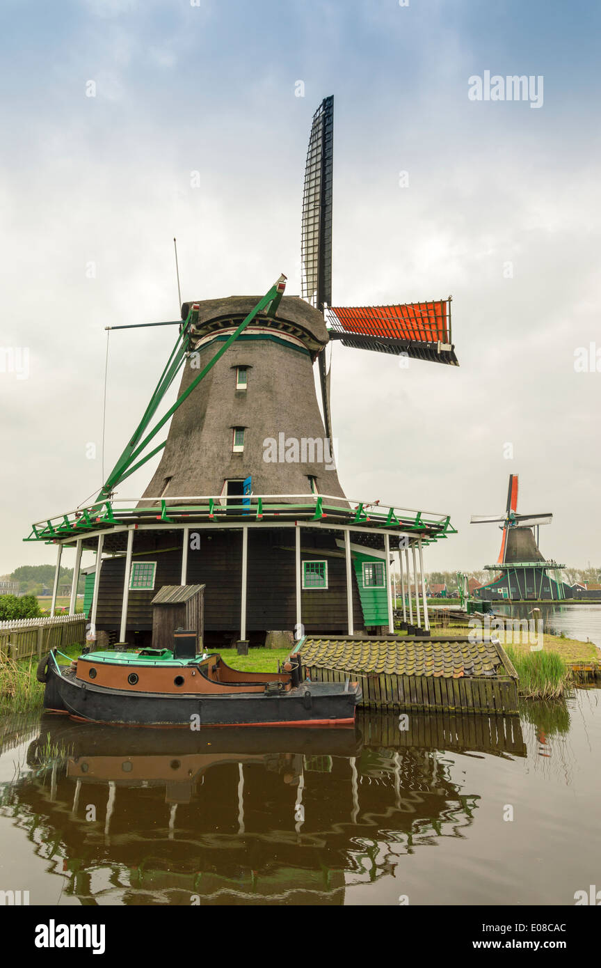 DUTCH WINDMILLS WITH ORANGE SAILS AND A BOAT ON THE CANAL AT ZAANSE SCHANS HOLLAND Stock Photo