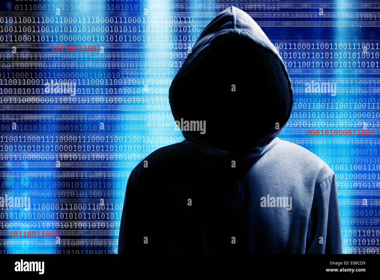 a hacker with a hood over a screen with binary code Stock Photo