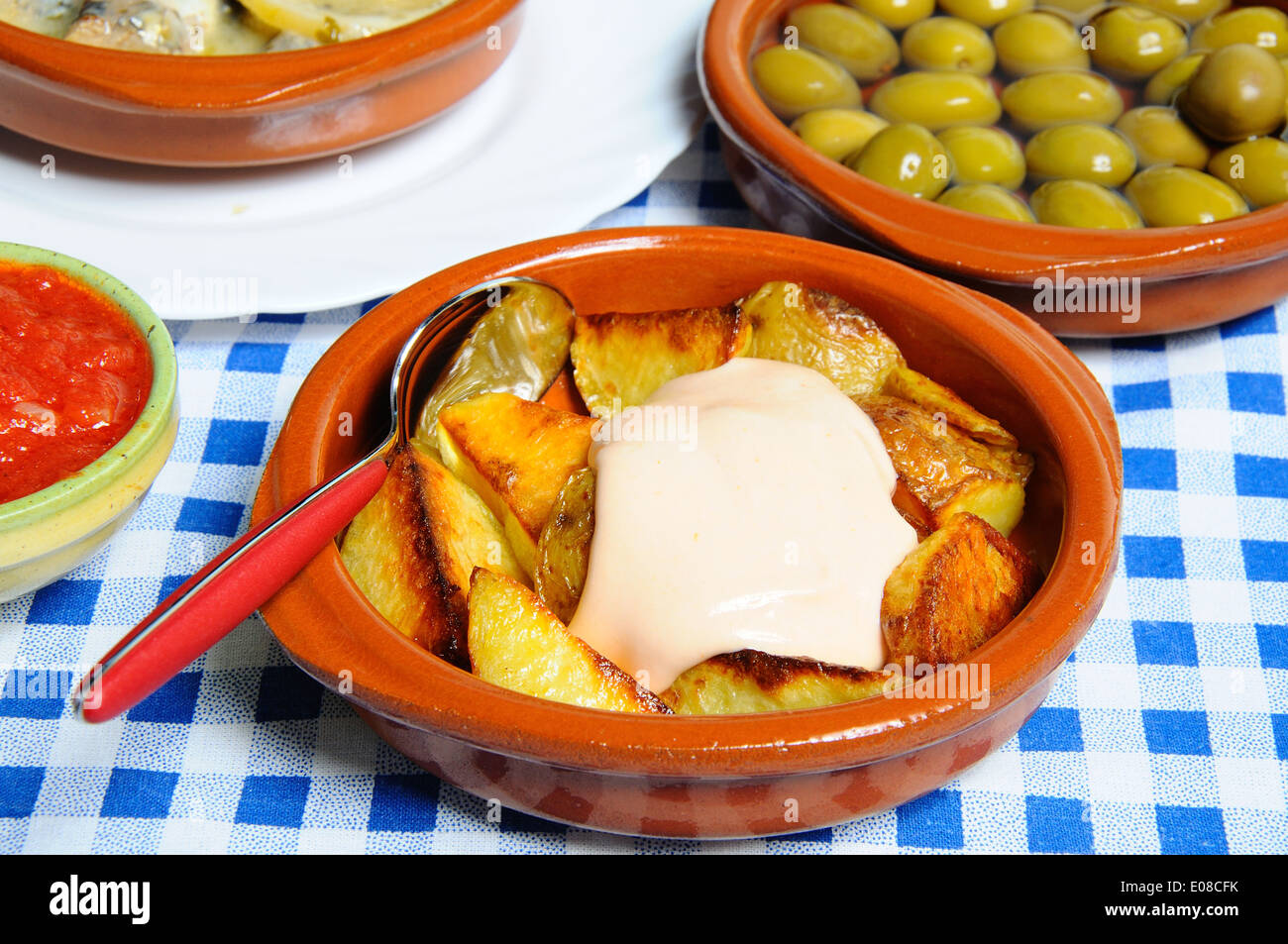Tapas - chipped potatoes with mayonnaise (Patatas Bravas) with green olives to the rear, Stock Photo
