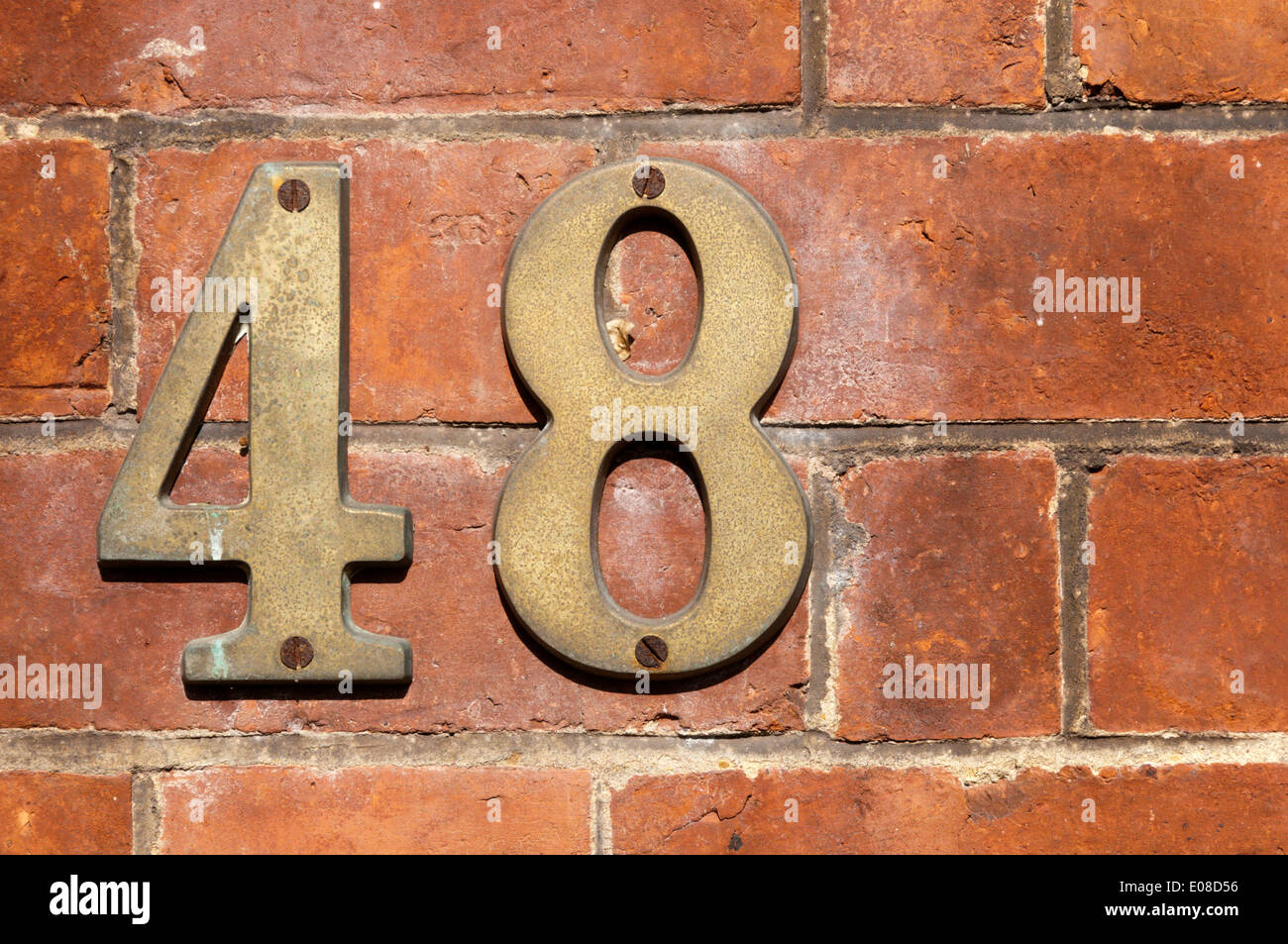 Metal number 48 fixed to a brick wall. Stock Photo