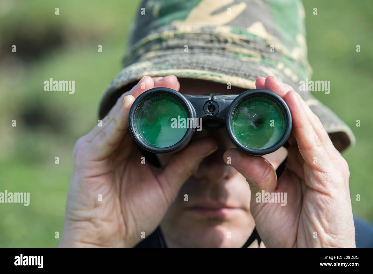 Male in camouflage hat looking through binoculars Stock Photo - Alamy
