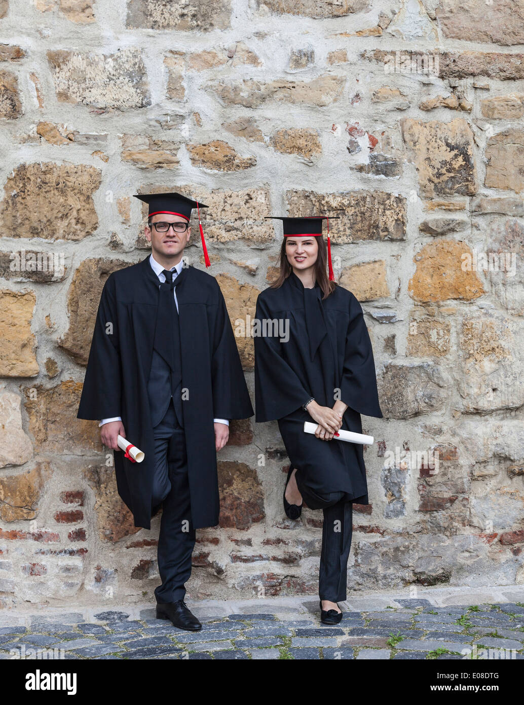 Young couple in the graduation day posing together near a rocky wall. Stock Photo