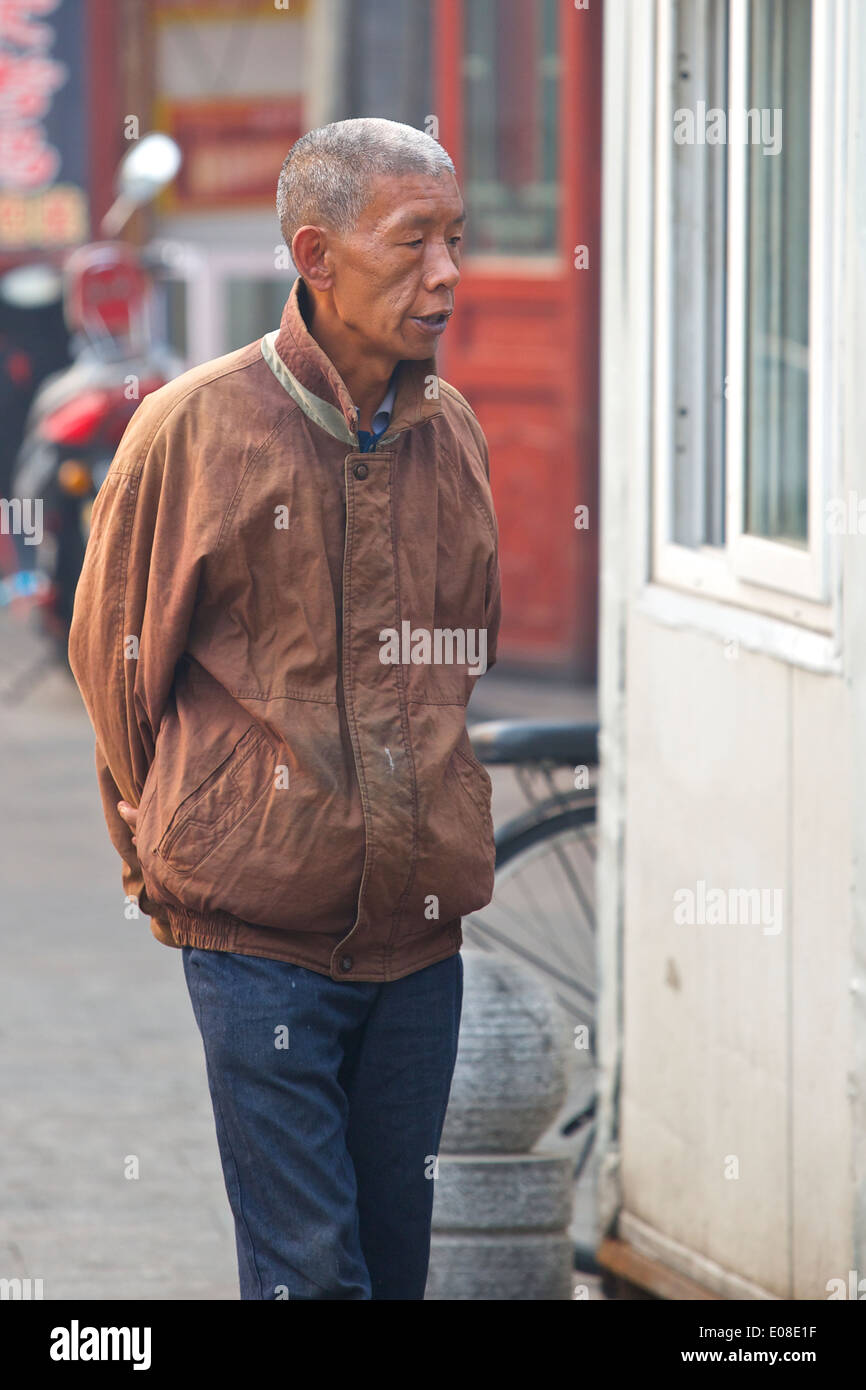 Elderly Chinese Man Walking Through The Historic Hutong Of Da Shi Lan, Beijing, China. Stock Photo