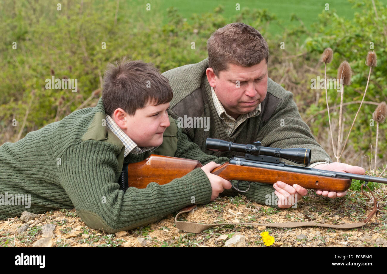 A young boy with an air rifle being coached in target shooting by his father Stock Photo
