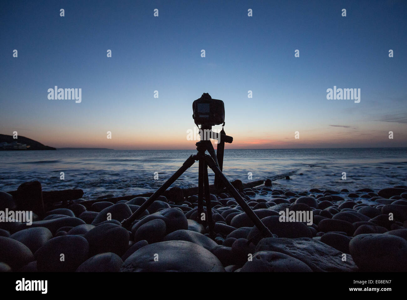 A camera on a tripod photographing the sunset at the beach in Devon UK ...