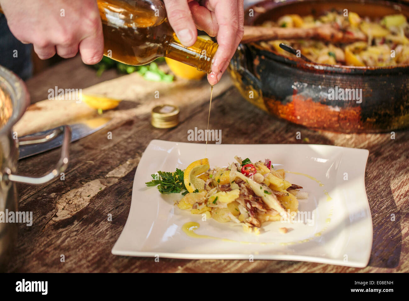 Person pouring olive oil on smoked pike dish Stock Photo