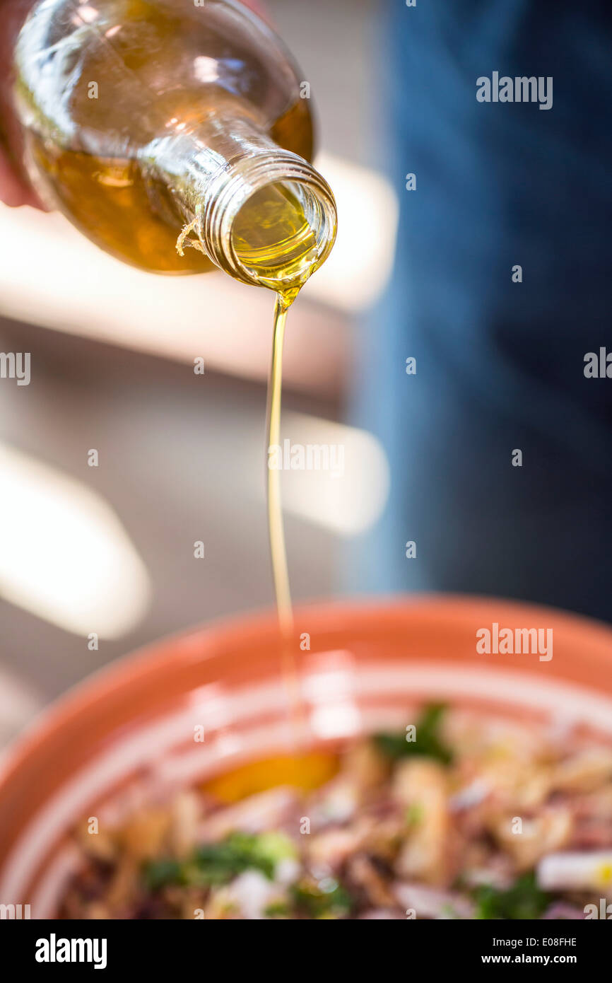 Person pouring olive oil into food Stock Photo