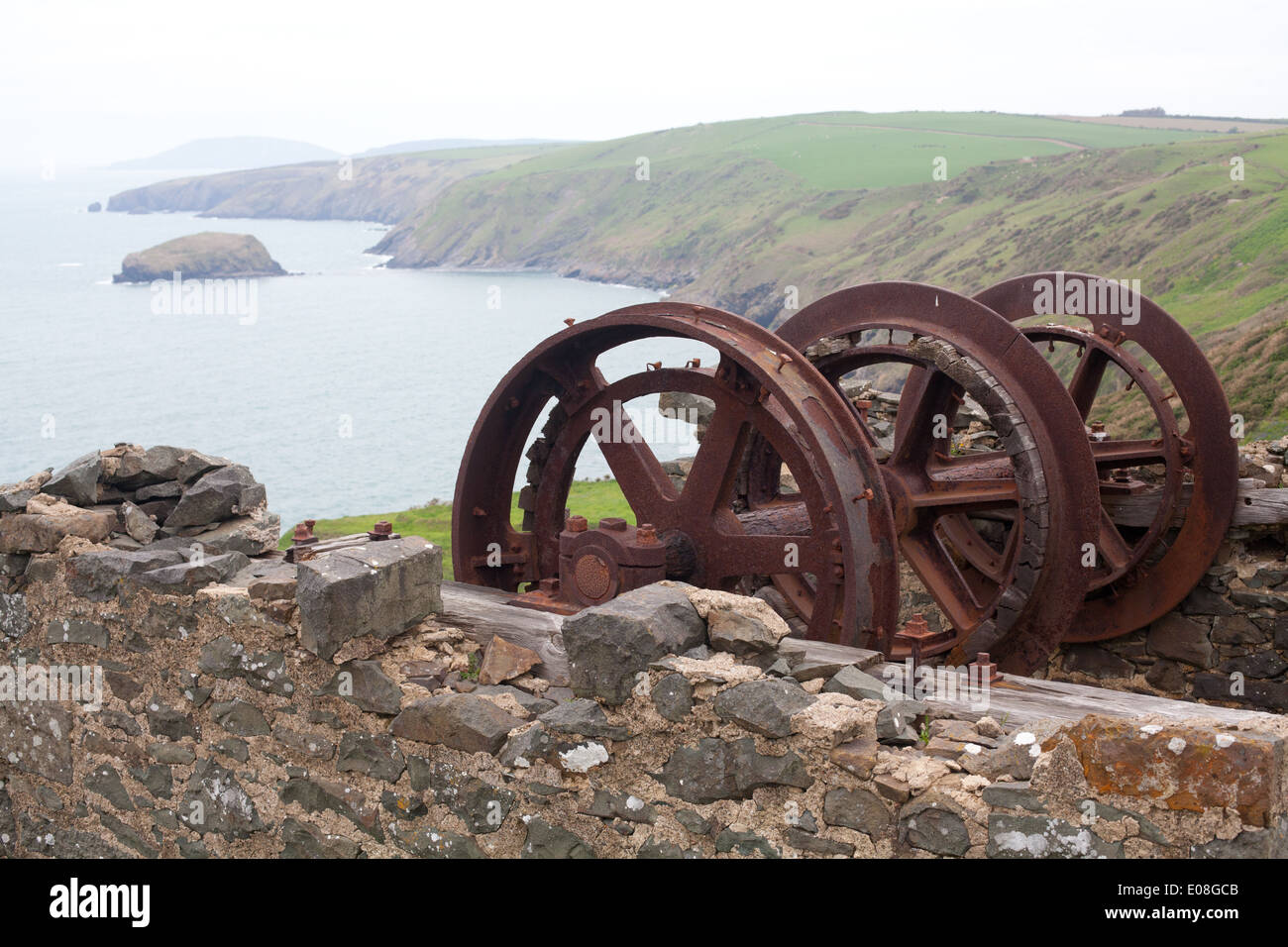 Old mine winding gear above Porth Ysgo looking across the cove / beach towards Aberdaron and Bardsey Island / Ynys Enlli Stock Photo