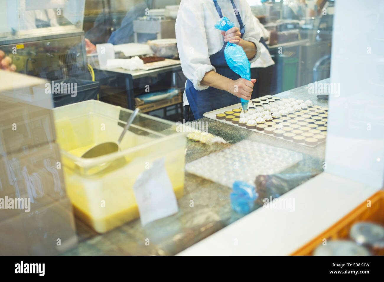 Midsection of female worker icing sweet food at display cabinet in cafe Stock Photo