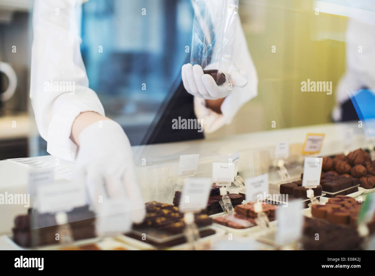 Midsection of female worker packing sweet food at display cabinet in cafe Stock Photo