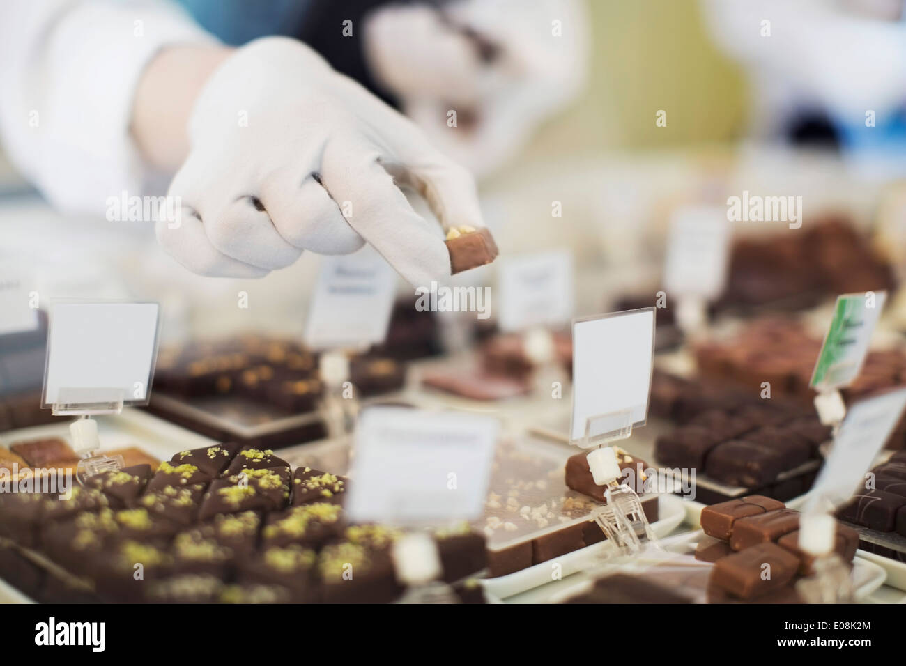 Cropped image of worker holding sweet food at display cabinet at cafe Stock Photo