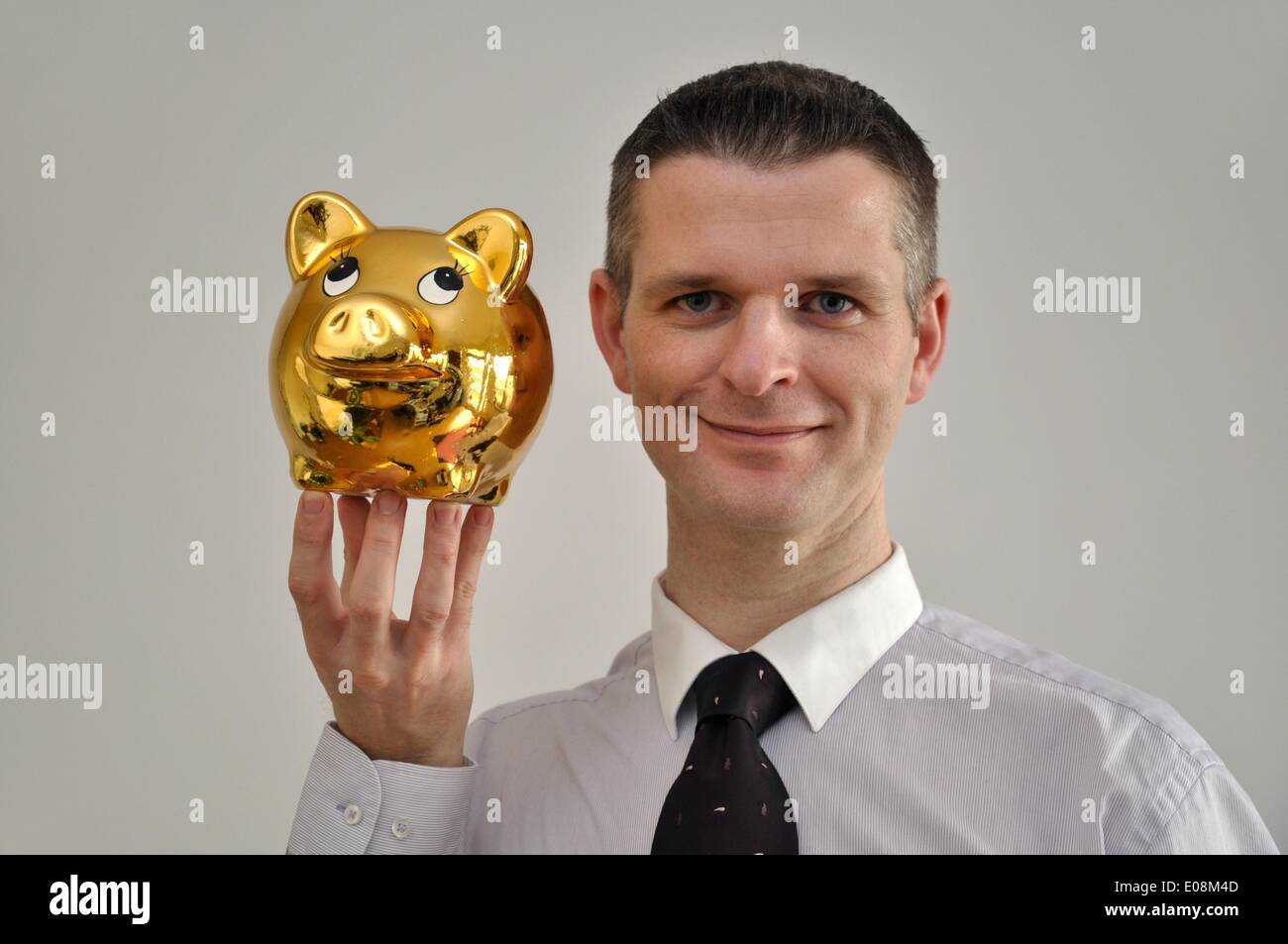 Illustration - A man holds a golden piggy bank in Germany, 27 February 2011. Fotoarchiv für Zeitgeschichte - NO WIRE SERVICE Stock Photo
