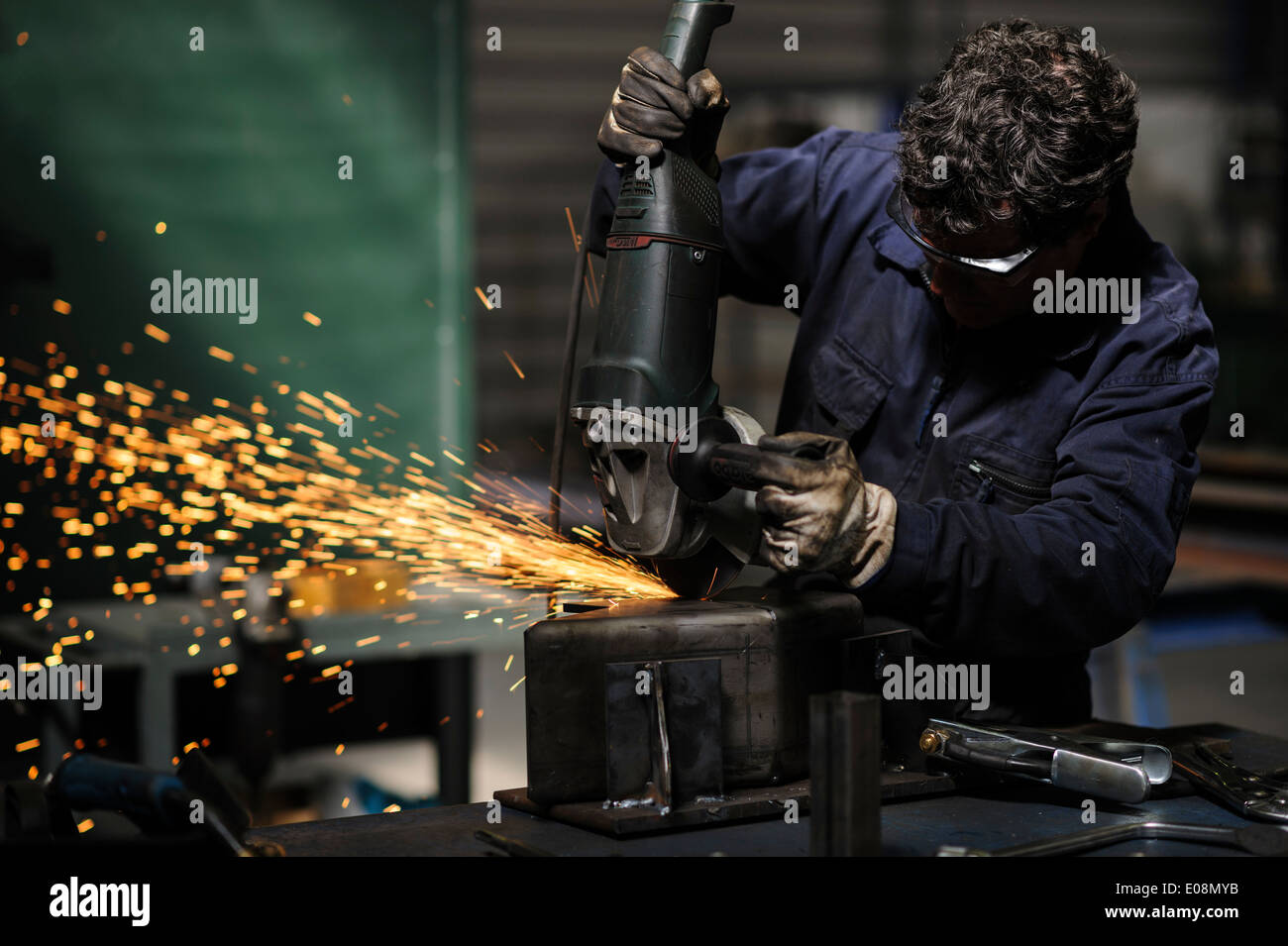 Factory worker using angle grinder to cut metal Stock Photo