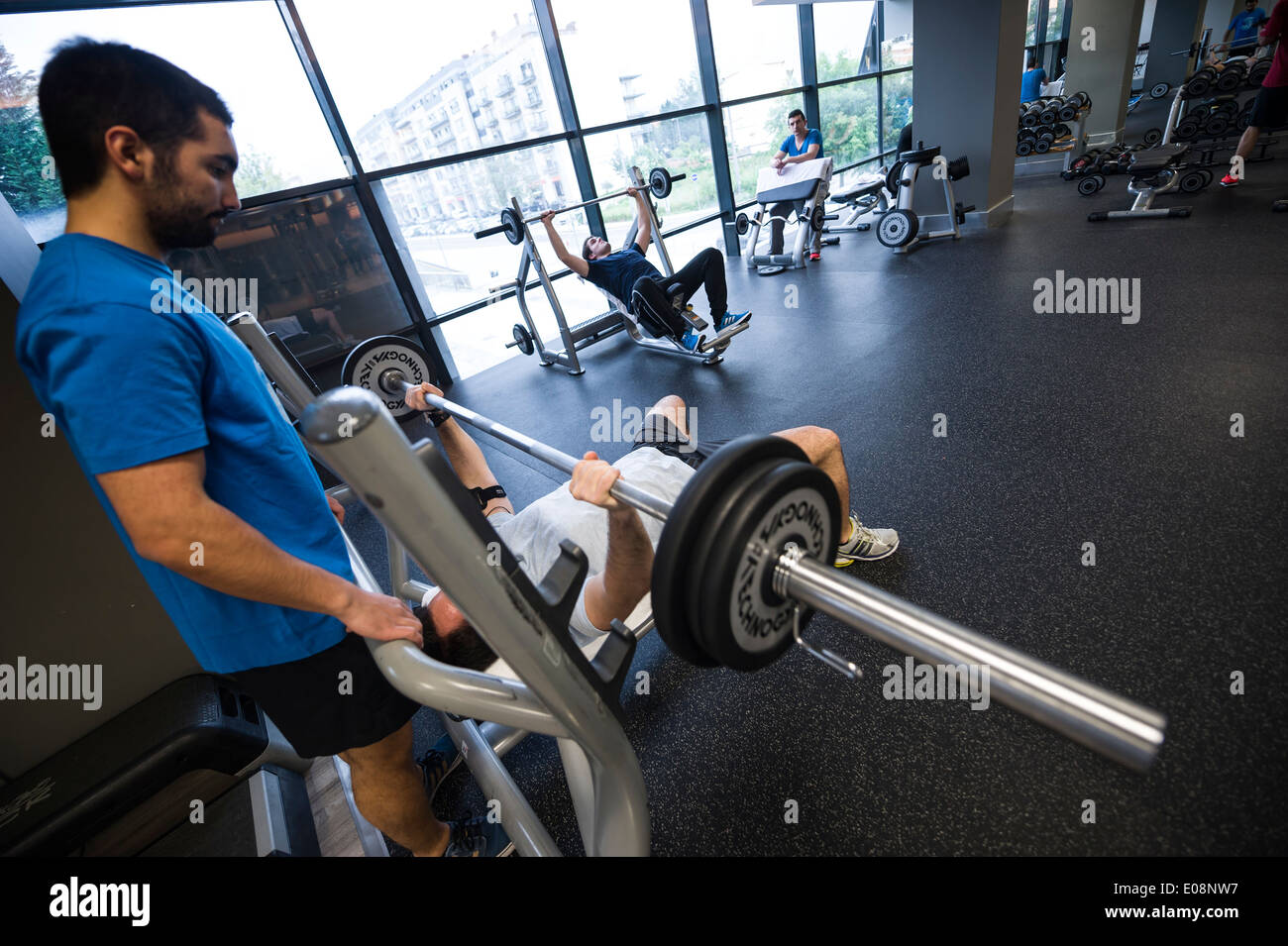 Man lifting weights at the gym with help of a spotter Stock Photo