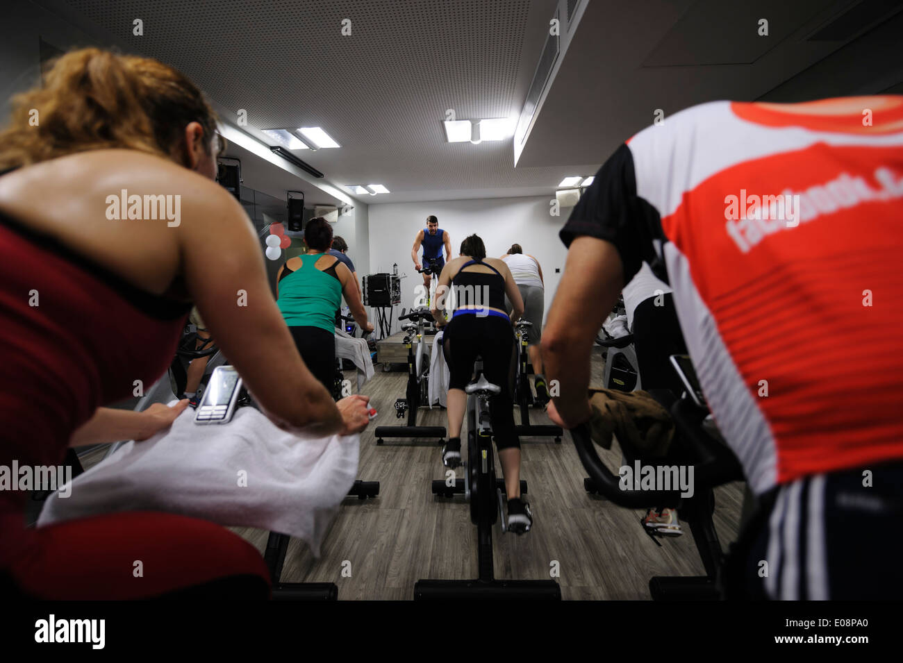 View from the back of people riding stationary bicycle during a spinning class at the gym Stock Photo