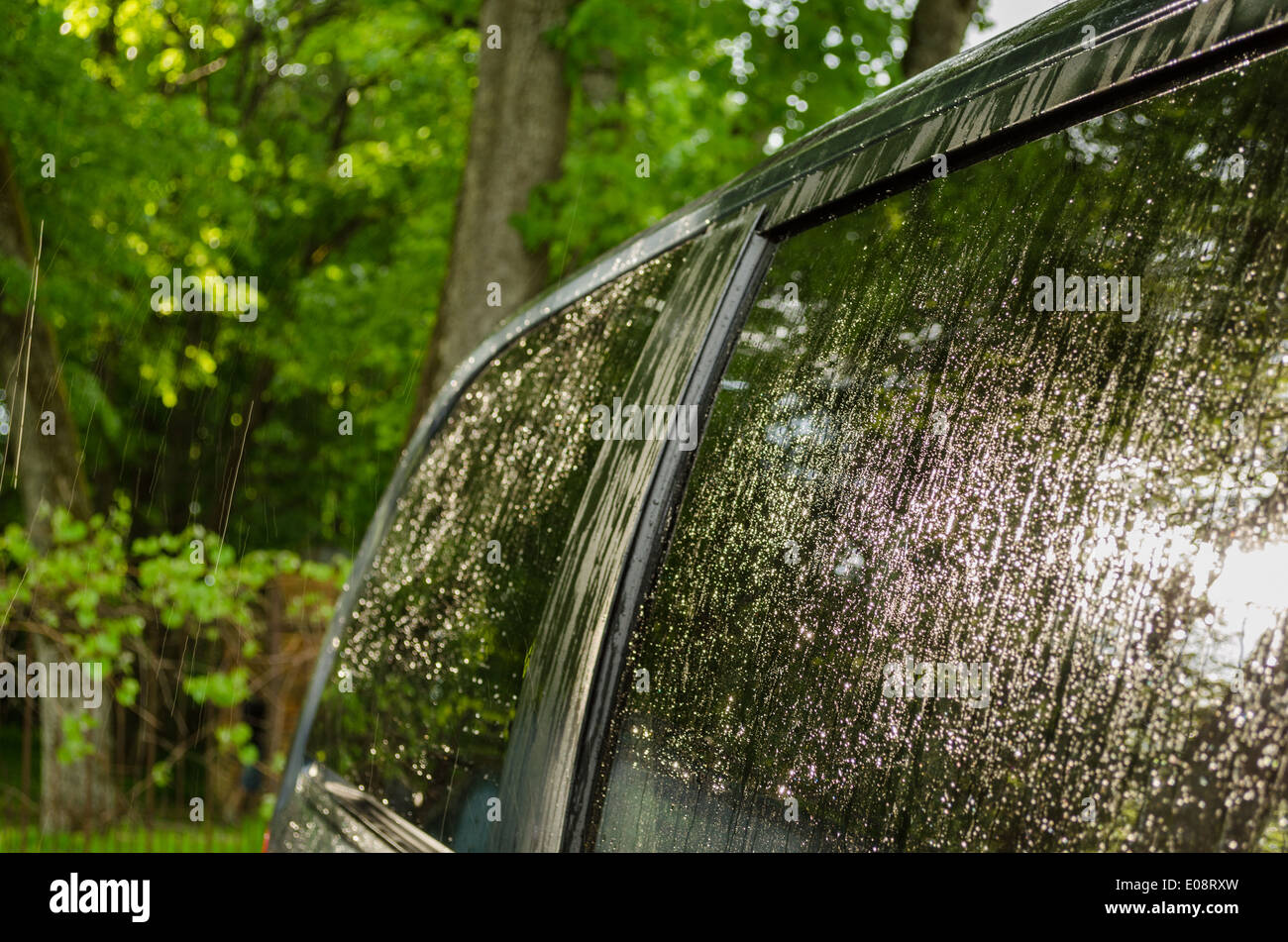 Strong rain water drops fall and splash on car roof and windows. Stock Photo